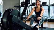 Eine junge Frau trainiert auf einer Rudermaschine im Fitnessstudio.