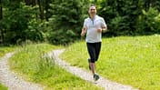 Ein Mann mittleren Alters joggt auf einem Feldweg.