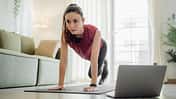 Cardio-Work-out zu Hause: Eine Frau macht Mountain Climber im Wohnzimmer.