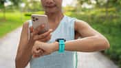 MET: das metabolische Äquivalent beim Laufen. Eine Läuferin checkt Lauf-Uhr und Lauf-App.