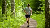 Das richtige Lauftempo: Junger Mann joggt durch lichten Wald